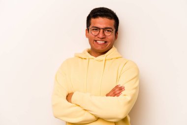 Beyaz arka planda kendini güvende hisseden, kararlılıkla kollarını kavuşturan genç İspanyol bir adam..