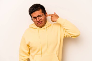 Beyaz arka planda izole edilmiş genç İspanyol adam kulaklarını elleriyle kapatıyor..