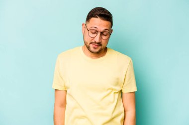 Mavi arka planda izole olmuş genç İspanyol adam gülüyor ve gözlerini kapıyor, rahatlamış ve mutlu hissediyor..