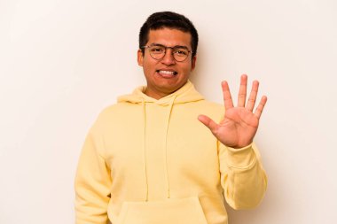 Beyaz arka planda izole edilmiş genç İspanyol adam gülümseyerek beş numarayı parmaklarıyla gösteriyor..