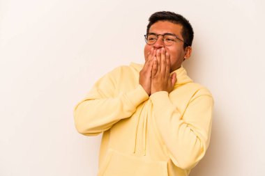 Beyaz arka planda izole edilmiş genç İspanyol bir adam bir şeye gülüyor, elleriyle ağzını kapatıyor..