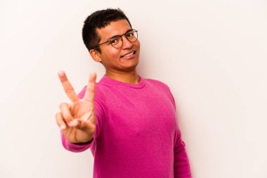 Beyaz arka planda izole edilmiş genç İspanyol adam neşeli ve kaygısız parmakları olan bir barış sembolü gösteriyor..