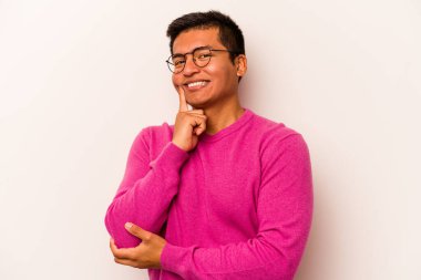 Beyaz arka planda izole olmuş genç İspanyol adam gülümsüyor ve kendinden emin, elleriyle çeneye dokunuyor..