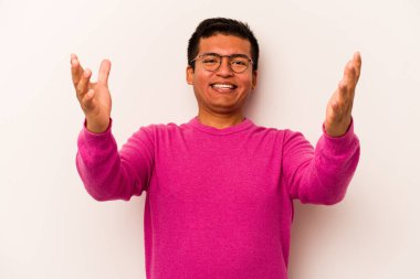 Latin kökenli genç bir adam zaferi ya da başarıyı kutlarken beyaz arka planda mahsur kaldı. Şaşırdı ve şok oldu..