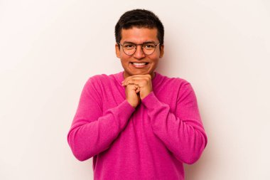 Beyaz arka planda izole edilmiş genç İspanyol adam ellerini çenesinin altında tutuyor ve mutlu bir şekilde yan tarafa bakıyor..