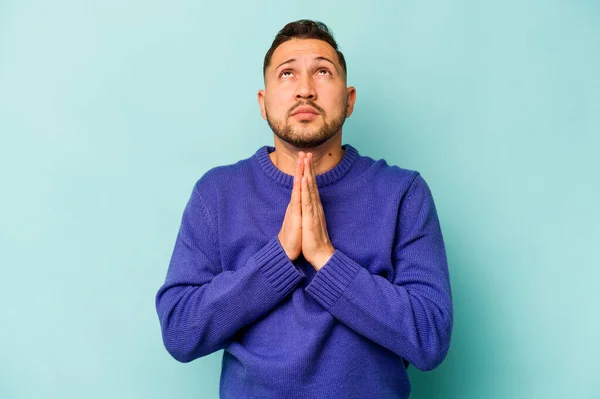 Joven Hombre Hispano Aislado Sobre Fondo Azul Tomados Mano Oración — Foto de Stock