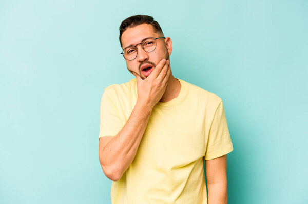 Young hispanic man isolated on blue background having a strong teeth pain, molar ache.
