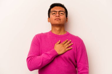 Genç İspanyol bir adam beyaz arka planda izole edilmiş yemin ediyor, elini göğsüne koyuyor..