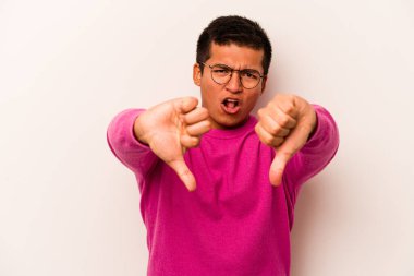 Beyaz arka planda izole edilmiş genç İspanyol adam baş parmağını aşağı gösteriyor ve hoşlanmadığını ifade ediyor..