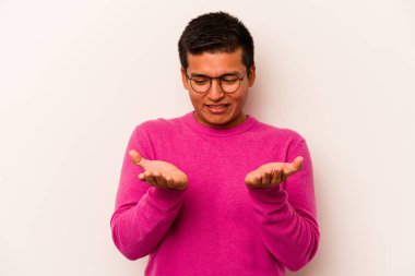 Beyaz arka planda izole edilmiş genç İspanyol bir adam avuçlarıyla bir şey tutuyor ve kameraya sunuyor..