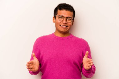 Beyaz arka planda izole edilmiş genç İspanyol adam iki eliyle bir şey tutuyor, ürün sunumu..