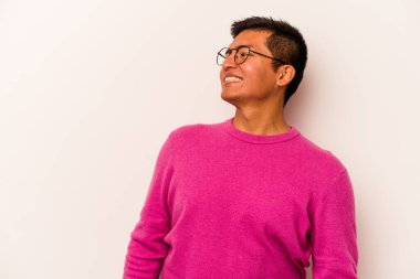 Beyaz arka planda izole edilmiş genç bir İspanyol. Rahatlamış ve mutlu bir şekilde gülüyor. Boynunda dişler var..