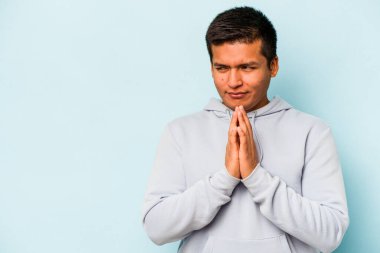 Latin kökenli genç bir adam mavi arka planda izole edildi. Aklında bir plan kuruyor, bir fikir kuruyor..