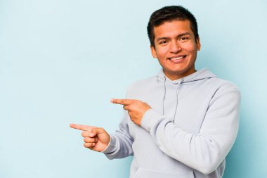 Mavi arka planda izole edilmiş genç bir İspanyol işaret parmaklarıyla işaret ederek heyecanlanıyor..