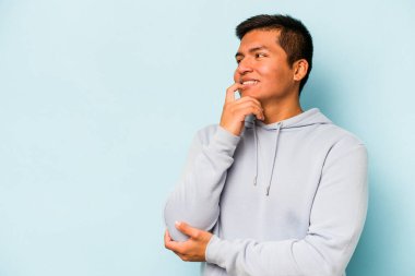 Mavi arka planda izole olmuş genç İspanyol bir adam rahatlamış bir şeyin fotokopi odasına baktığını düşünüyor..