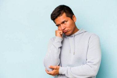 Mavi arka planda izole edilmiş, üzgün ve dalgın hisseden genç bir İspanyol fotokopi odasına bakıyor..