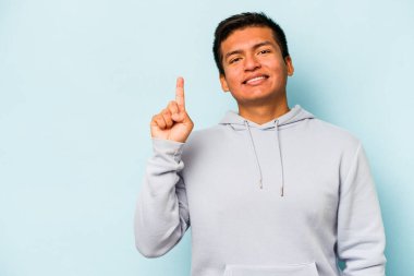 Mavi arka planda izole edilmiş genç İspanyol bir numara parmağıyla görünüyor..