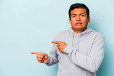 Mavi arka planda izole edilmiş genç İspanyol adam işaret parmağıyla fotokopi alanını işaret ederek şok oldu..