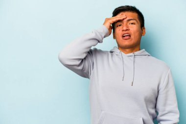 Mavi arka planda izole edilmiş genç bir İspanyol yüksek sesle bağırıyor, gözleri açık ve elleri gergin tutuyor..