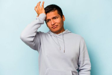 Mavi arka planda izole edilmiş genç İspanyol bir adam bir şeyi unutuyor. Alnına avuç içi ile vuruyor ve gözlerini kapıyor..