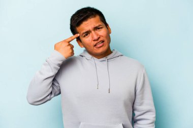Mavi arka planda izole edilmiş genç İspanyol adam işaret parmağıyla bir hayal kırıklığı gösteriyor..