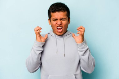 Genç İspanyol adam mavi arka planda izole edilmiş öfkeyle bağırıyor..