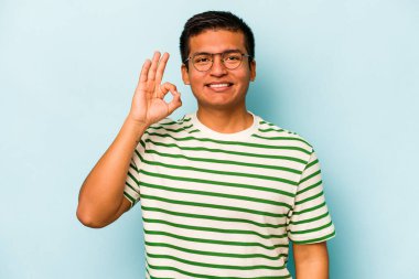 Genç İspanyol adam mavi arka planda izole edilmiş neşeli ve kendine güvenen iyi bir hareket sergiliyor..