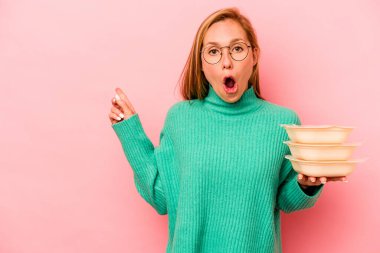 Tupperware taşıyan beyaz bir kadın. Pembe arka planda izole edilmiş. Yan tarafı gösteriyor.