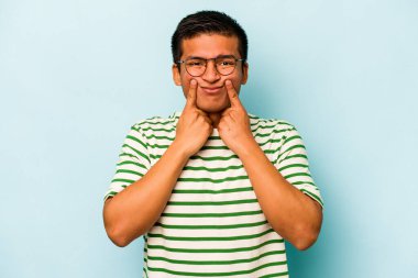 Latin kökenli genç bir adam mavi arka planda iki seçenek arasında kuşkulanıyor..