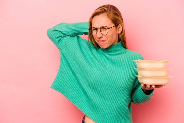 Beyaz tenli genç bir kadın pembe arka planda saklanmış vaziyette kafasının arkasına dokunuyor, düşünüyor ve bir seçim yapıyor..