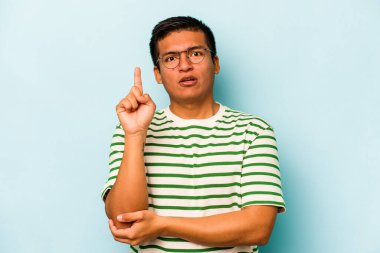 Latin kökenli genç bir adam mavi arka planda izole edilmiş. Harika bir fikri var, yaratıcılık kavramı..