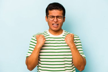 Genç İspanyol adam mavi arka planda izole edilmiş kaygısız ve heyecanlı tezahüratlar yapıyor. Zafer konsepti.