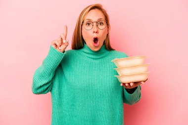 Beyaz tenli genç bir kadın pembe arka planda saklanmış vaziyette. Bir fikri, ilham verici bir fikri var..