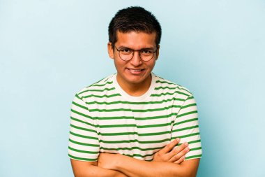 Genç İspanyol adam mavi arka planda izole edilmiş gülüyor ve eğleniyor..