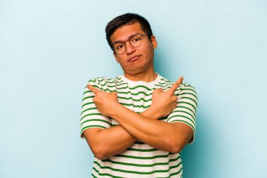 Mavi arka plan noktalarında izole edilmiş genç İspanyol adam iki seçenek arasında seçim yapmaya çalışıyor..