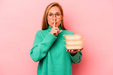 Beyaz tenli genç bir kadın pembe arka planda saklanmış saklama ya da sessizlik istiyor..