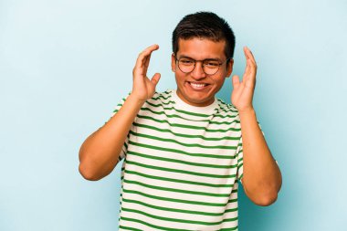 Genç İspanyol adam mavi arka planda izole edilmiş neşeli bir şekilde gülüyor. Mutluluk kavramı.