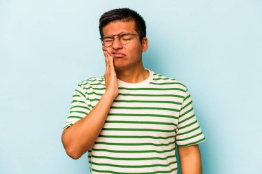 Genç İspanyol bir adam mavi arka planda izole edilmiş güçlü bir diş ağrısı, azıdişi ağrısı var..