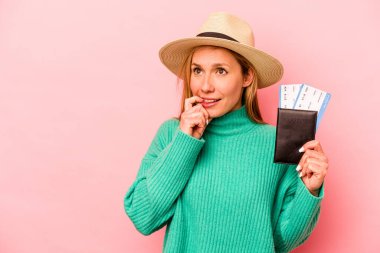 Pembe arka planda izole edilmiş pasaport taşıyan beyaz bir kadın rahatlamış fotokopi odasına bakan bir şey düşünüyor..