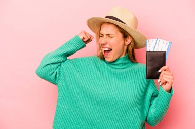 Pembe arka planda izole edilmiş pasaport taşıyan beyaz bir kadın zafer kazandıktan sonra yumruğunu kaldırıyor..