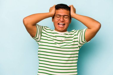 Genç İspanyol adam mavi arka planda izole edilmiş bağırıyor, çok heyecanlı, tutkulu, bir şeyden memnun..