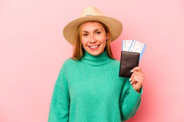 Pasaportu olan beyaz bir kadın pembe arka planda izole edilmiş mutlu, güler yüzlü ve neşeli..