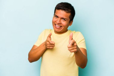 Mavi arka planda izole edilmiş genç İspanyol adam parmaklarıyla öne işaret ediyor..