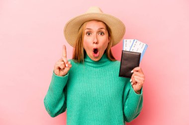 Pembe arka planda pasaport taşıyan beyaz bir kadın. Harika bir fikri var. Yaratıcılık kavramı..