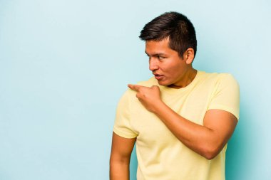 Genç İspanyol adam mavi arka planda izole edilmiş başparmak uzakta, gülüyor ve kaygısız.