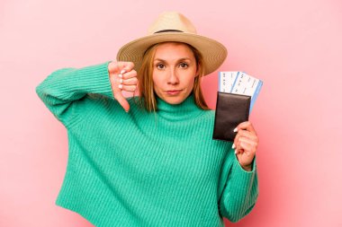 Pasaportu olan beyaz bir kadın pembe arka planda izole edilmiş, hoş olmayan bir jest gösteriyor. Anlaşmazlık konsepti.