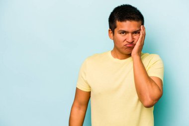 Mavi arka planda izole edilmiş, üzgün ve dalgın hisseden genç bir İspanyol fotokopi odasına bakıyor..