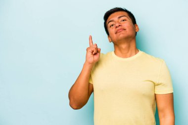 Mavi arka planda izole edilmiş genç İspanyol bir numara parmağıyla görünüyor..