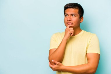 Mavi arka planda izole olmuş genç İspanyol bir adam rahatlamış bir şeyin fotokopi odasına baktığını düşünüyor..