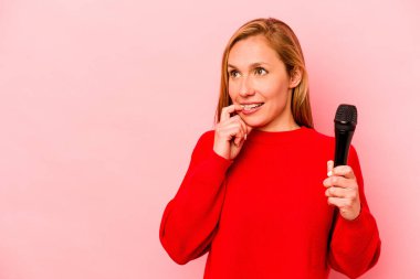 Pembe arka planda izole edilmiş genç beyaz kadın rahatça fotokopi odasına bakan bir şey düşünüyor..